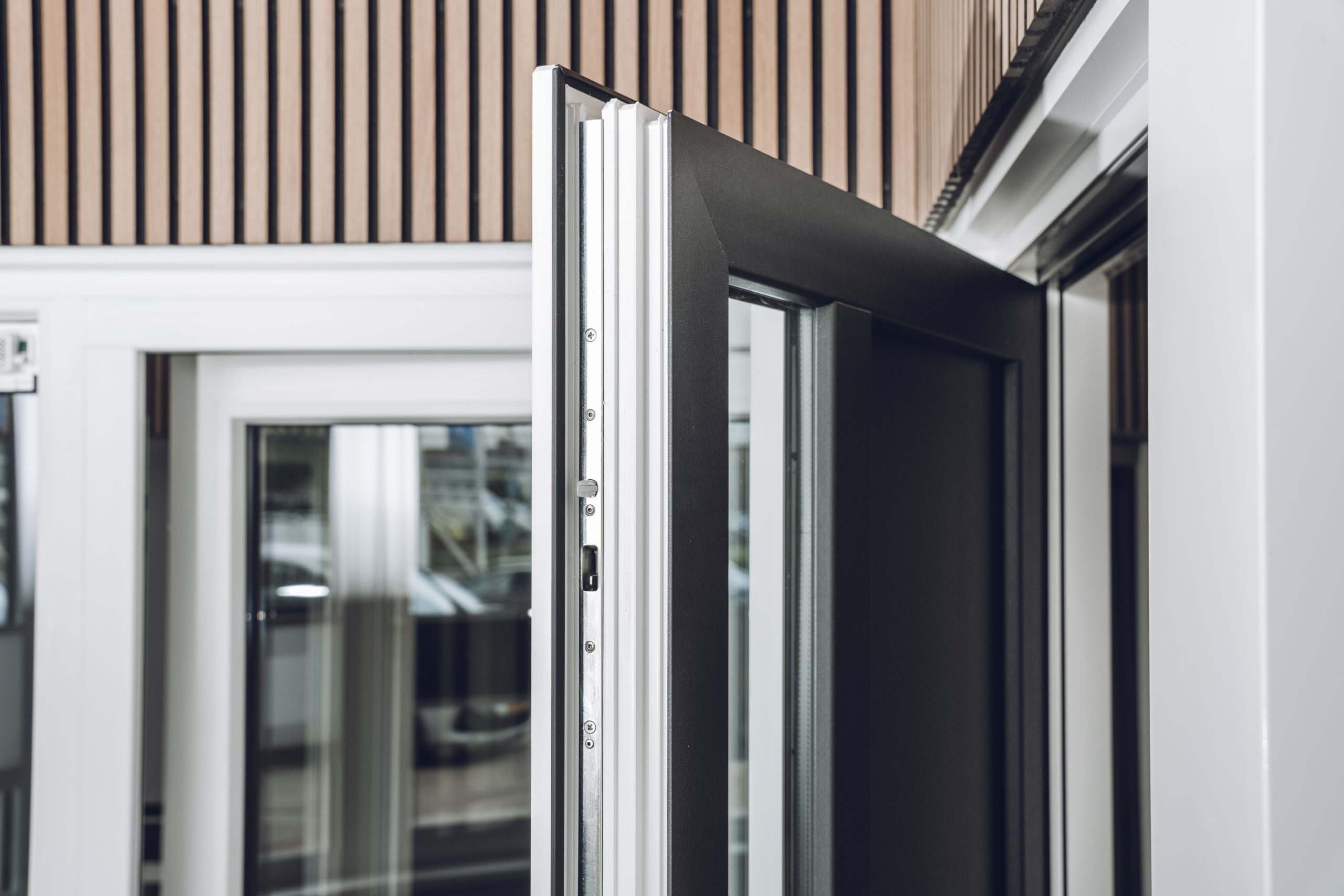 Skodora zwarte openstaande deur met witte kozijnen in houten muur